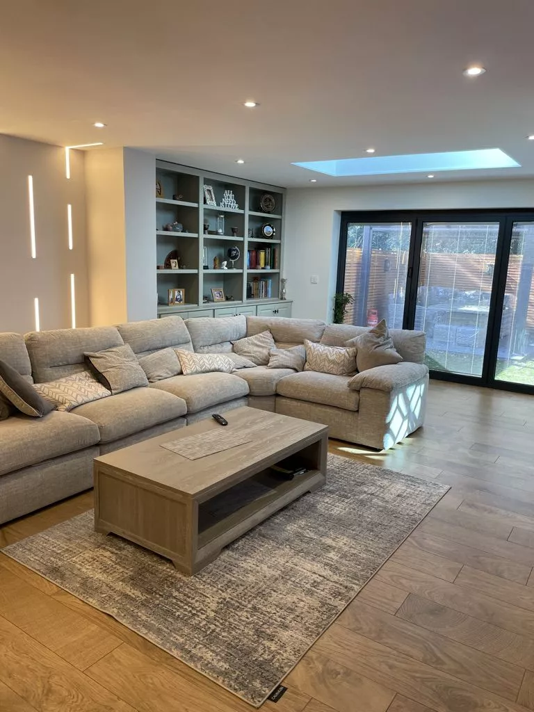 Finished Control4 living room in daylight with sofa, shelving and garden doors